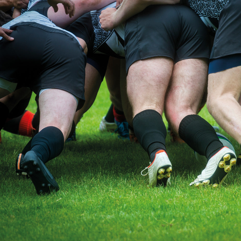 Close-up of rugby players in a scrum on a grass field
