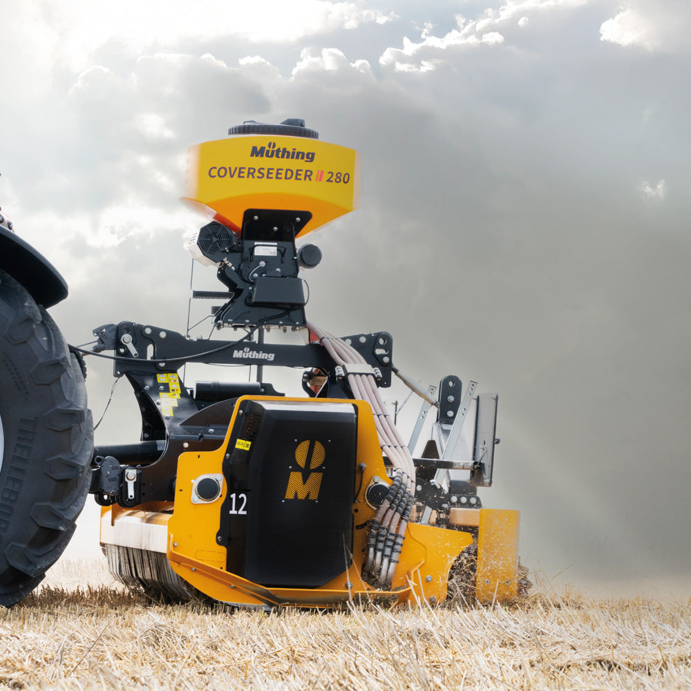 Yellow MÖthing cover seeder on a field with a cloudy sky.